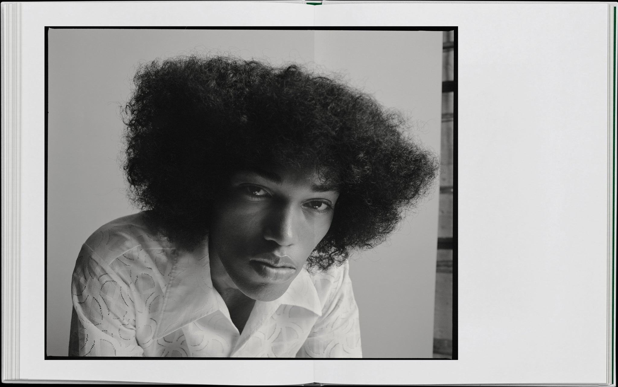 Book layout. Double Spread. A portrait of a man in a white shirt. He has an afro that is flattened along the top.